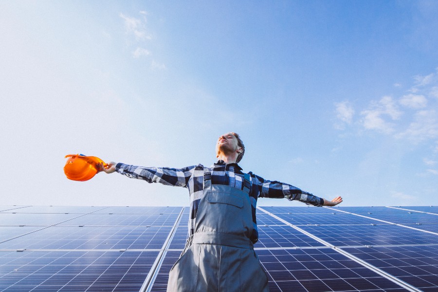 Engenheiro de braços abertos em frente a painéis de energia solar representando solar power